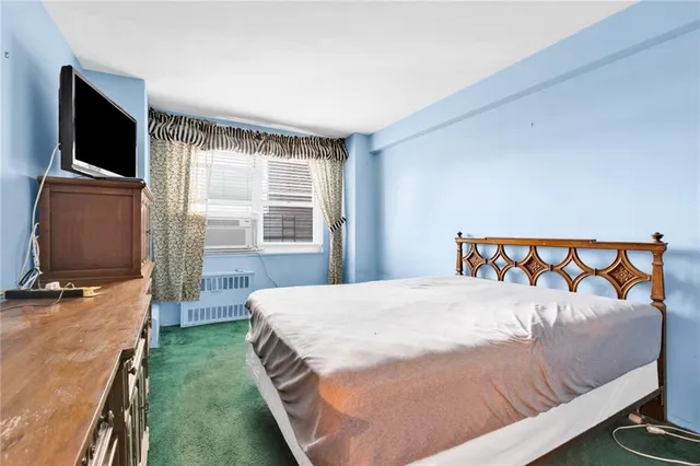 a bedroom with a large bed and a flat tv screen on dresser