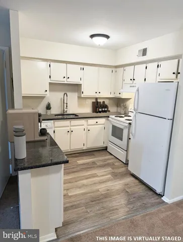 a kitchen with a sink a stove a refrigerator and white cabinets