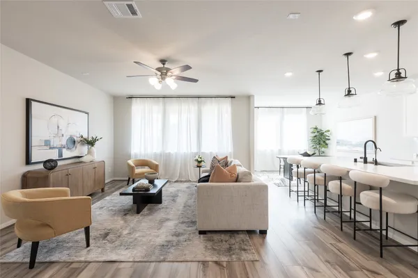 a living room with furniture kitchen view and a large window