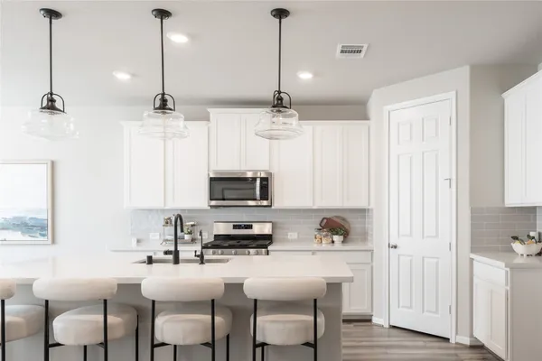 a kitchen with stainless steel appliances kitchen island granite countertop a sink a stove a microwave a dining table and chairs