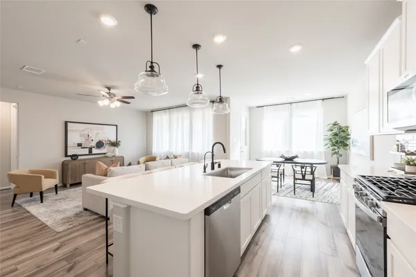 a large kitchen with kitchen island a stove a sink a dining table and chairs with wooden floor