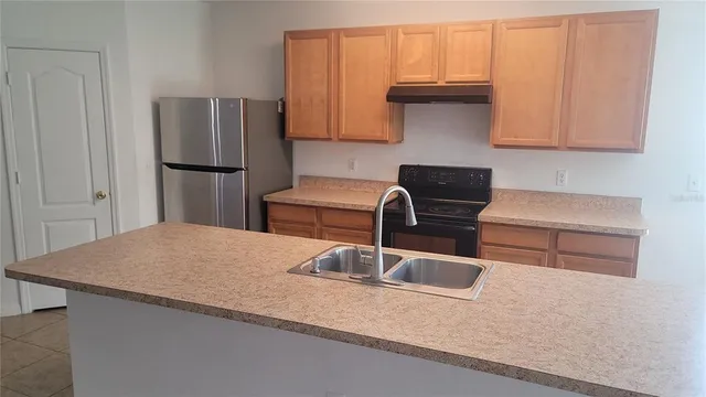 a kitchen with stainless steel appliances granite countertop a sink a refrigerator and a granite counter tops