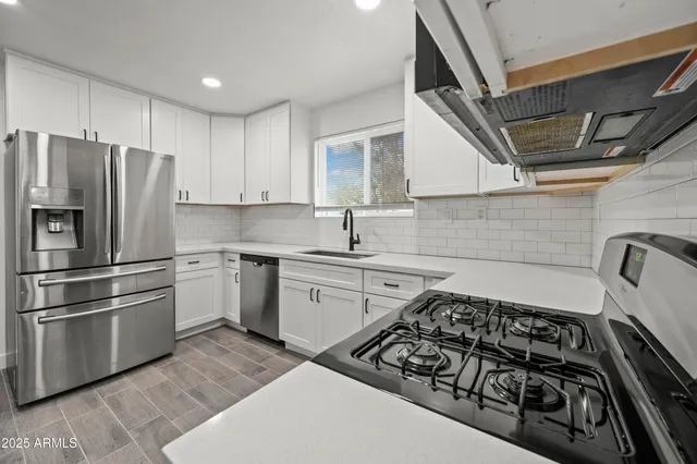 a kitchen with granite countertop a sink stove and refrigerator