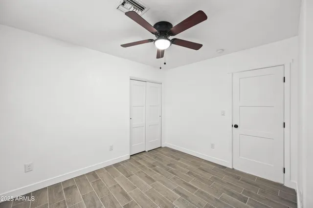 an empty room with wooden floor and ceiling fan