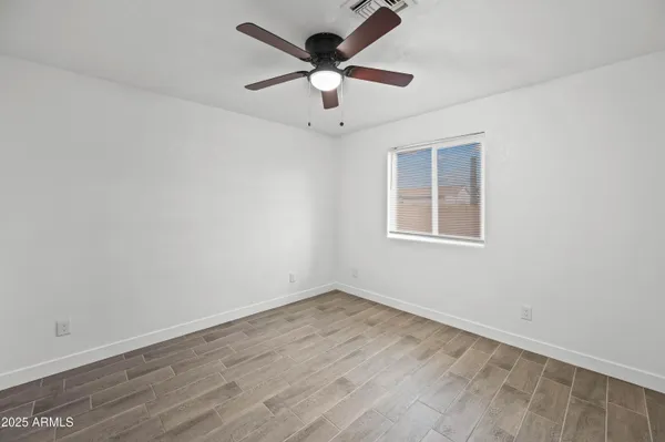 an empty room with wooden floor and ceiling fan