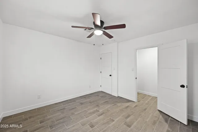 a view of empty room with wooden floor and ceiling fan