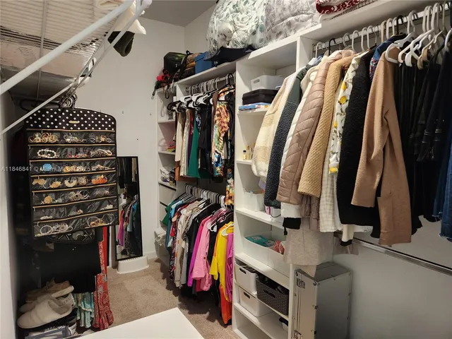 a view of walk in closet with clothes and shoes