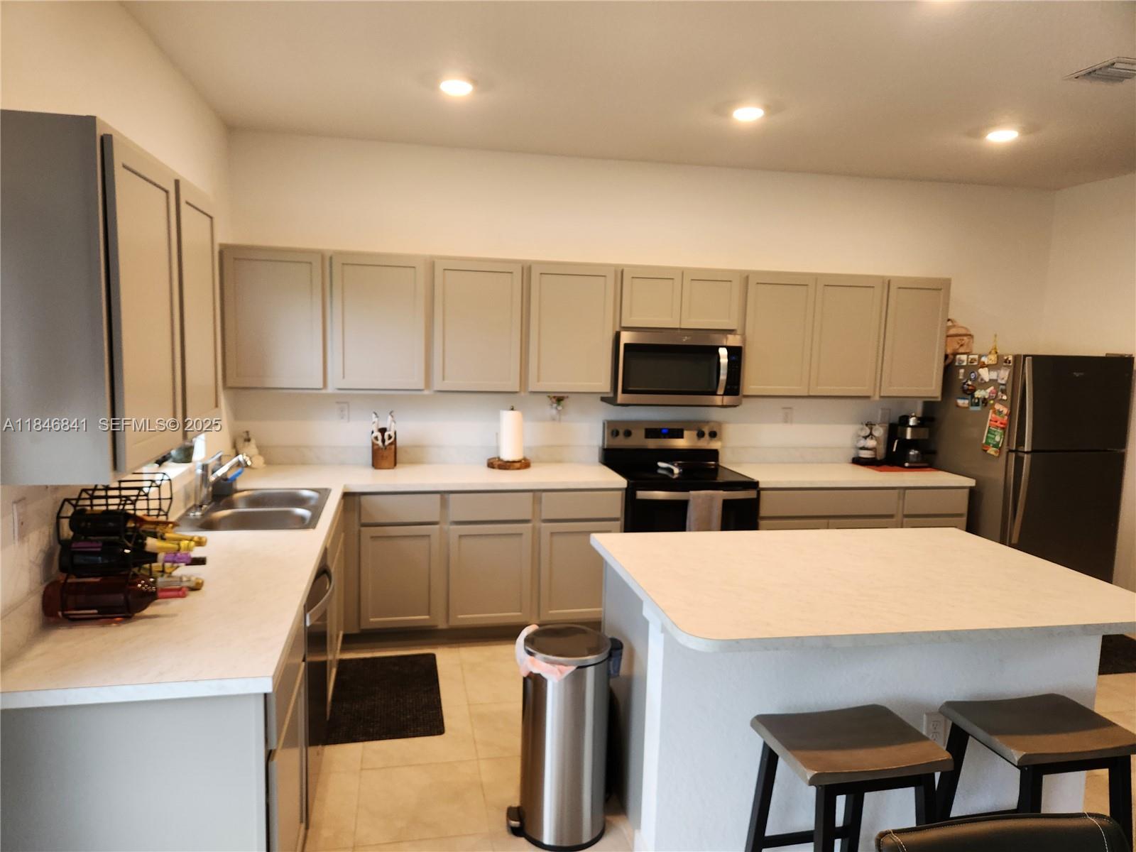 880 Northwest 3rd Way, Unit 880 Pompano Beach, FL 33060 - Photo 3 of 34 a kitchen with a sink a stove and chairs