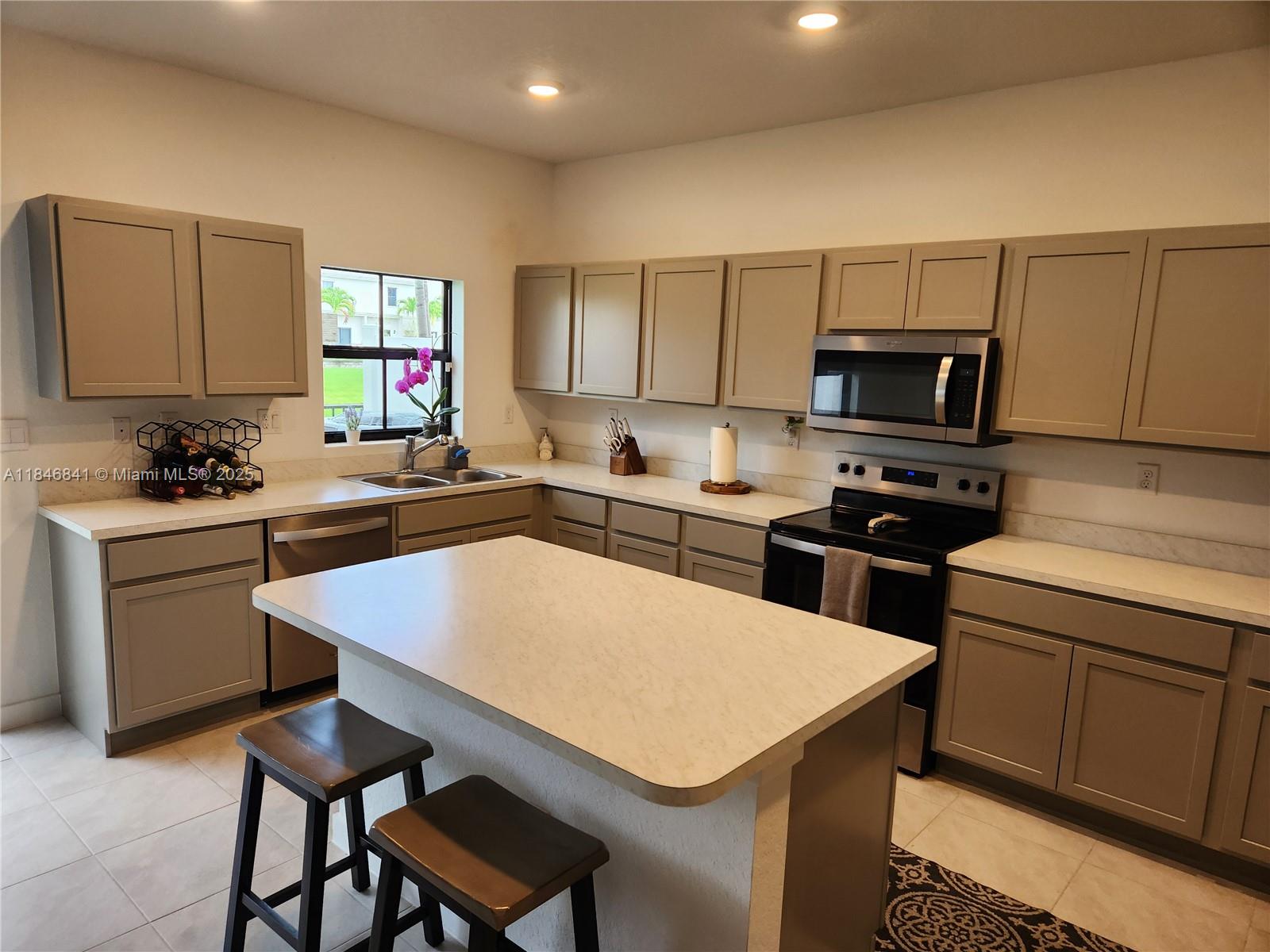 880 Northwest 3rd Way, Unit 880 Pompano Beach, FL 33060 - Photo 4 of 34 a kitchen with a sink a stove a kitchen island and chairs