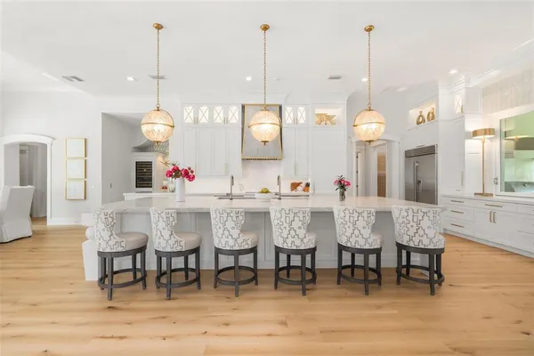 a kitchen with stainless steel appliances kitchen island granite countertop a sink a stove a dining table and chairs with wooden floor