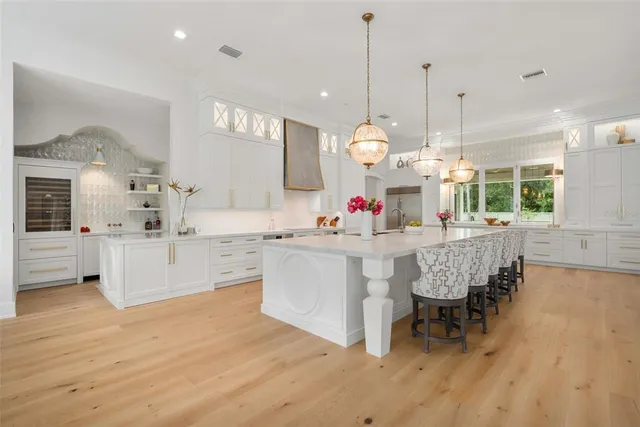 a large white kitchen with lots of counter space and chandelier