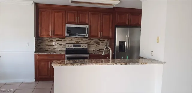 a kitchen with granite countertop a stove microwave and refrigerator