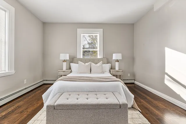 a large white bed in a white room next to a window