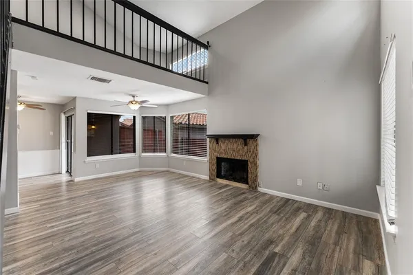 a view of an empty room with wooden floor fireplace and a window