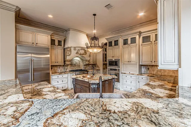 a kitchen with stainless steel appliances kitchen island granite countertop a refrigerator stove top oven and sink
