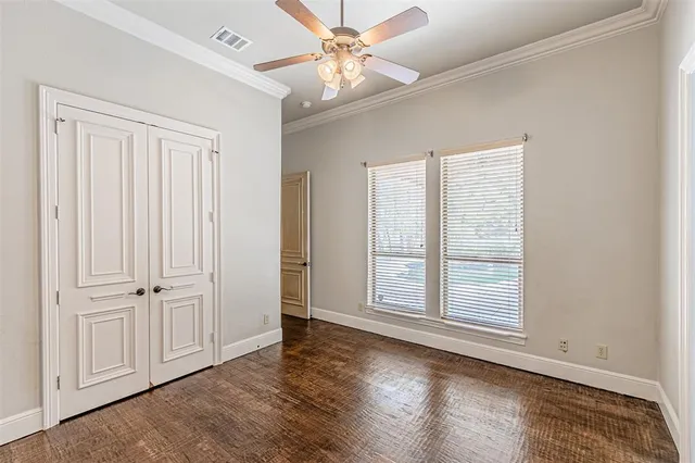 an empty room with wooden floor closet and windows