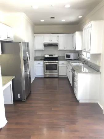 a large kitchen with stainless steel appliances granite countertop a refrigerator a stove a sink and a microwave
