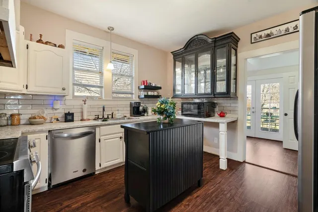 a kitchen with kitchen island granite countertop a sink cabinets and wooden floor