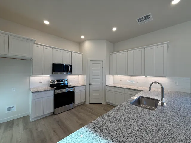 a kitchen with stainless steel appliances a sink a stove a microwave a sink a refrigerator and cabinets