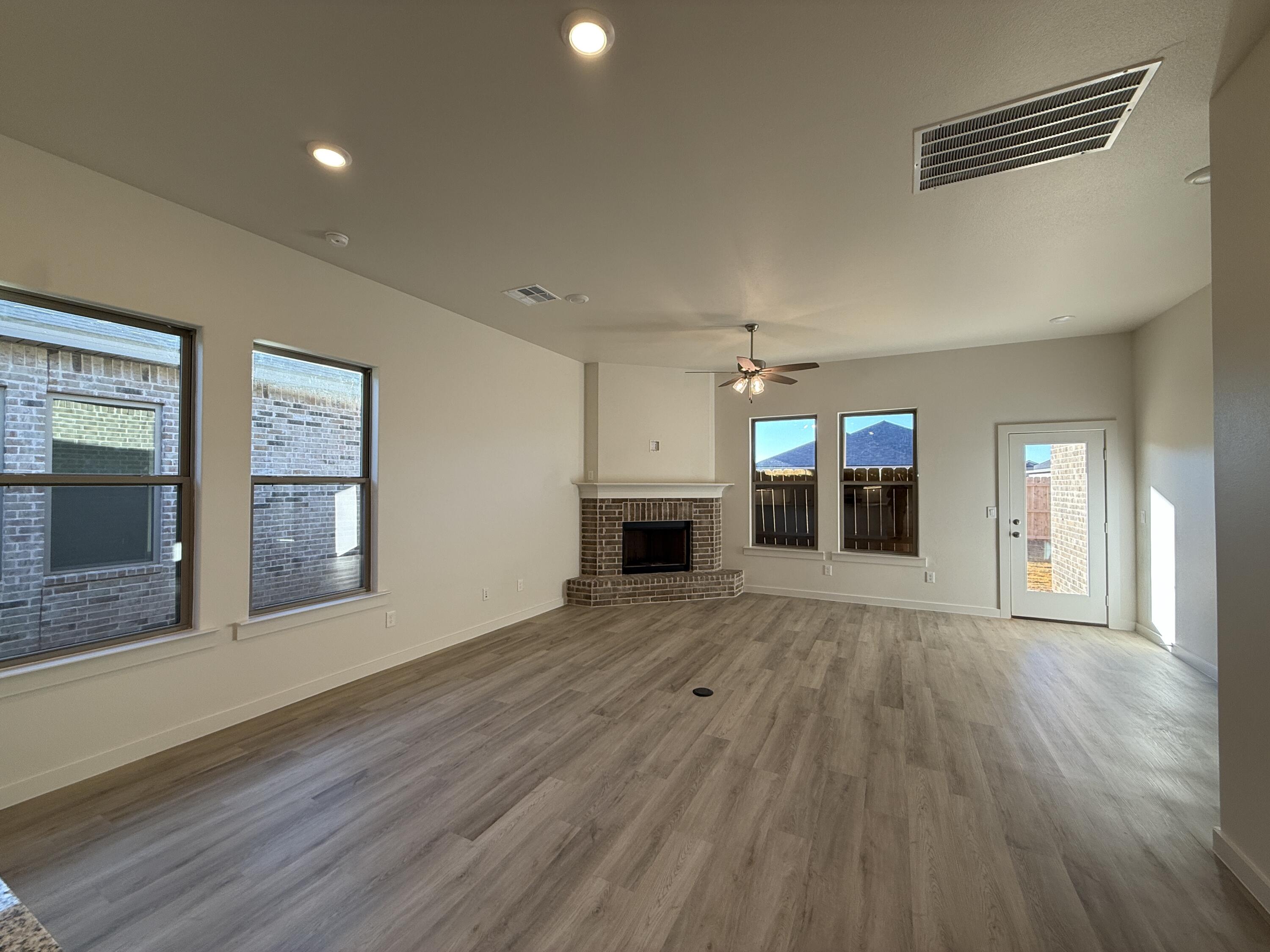 3003 138th Place Lubbock, TX 79423 - Photo 5 of 14 an empty room with wooden floor and fireplace