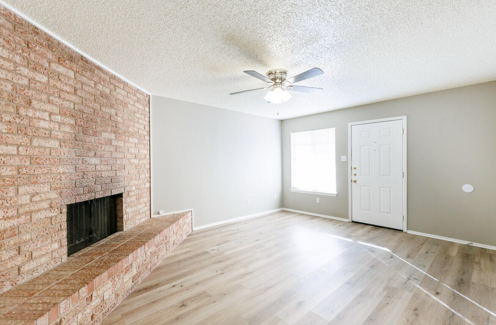 6112 38th Street, Unit A Lubbock, TX 79407 - Photo 3 of 15 an empty room with windows fireplace and wooden floor