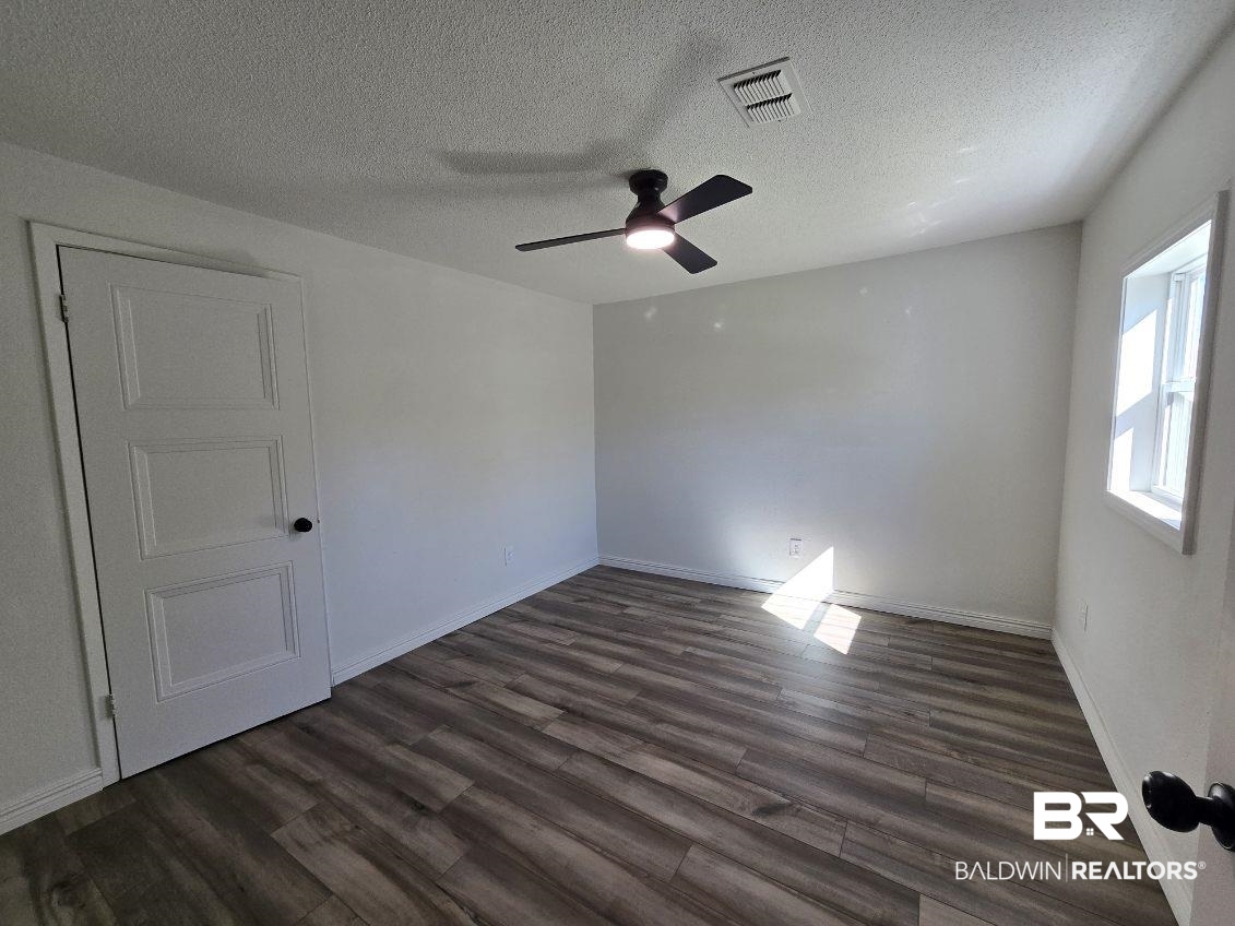 821 Dailey Street Brewton, AL 36426 - Photo 15 of 17 Empty room featuring a textured ceiling, dark wood-type flooring, and ceiling fan