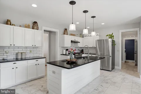 a kitchen with stainless steel appliances kitchen island granite countertop a stove top oven a sink a dining table and chairs