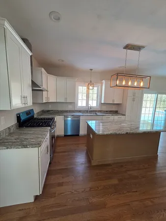 a kitchen with stainless steel appliances granite countertop a sink dishwasher a stove top oven a refrigerator with wooden floors