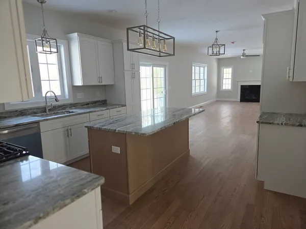 a kitchen with granite countertop stainless steel appliances white cabinets granite counter tops and a wooden floor