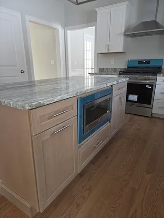 a large kitchen with a wooden floor and a view of living room