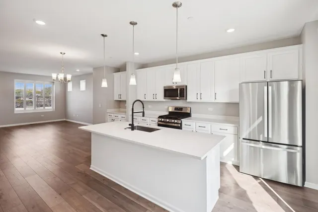 a kitchen with stainless steel appliances granite countertop a refrigerator a sink dishwasher a stove and white cabinets with wooden floor