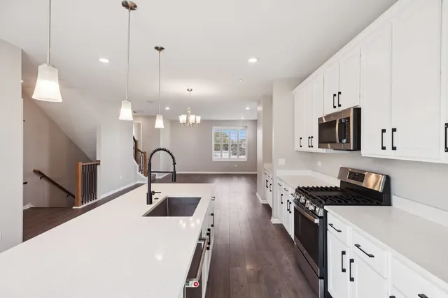 a kitchen with stainless steel appliances a stove a sink a microwave a counter space and cabinets