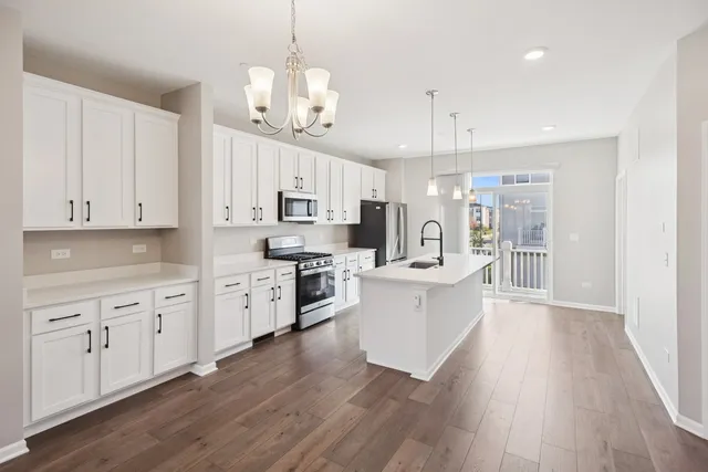 a large kitchen with white cabinets stainless steel appliances a sink and a center island