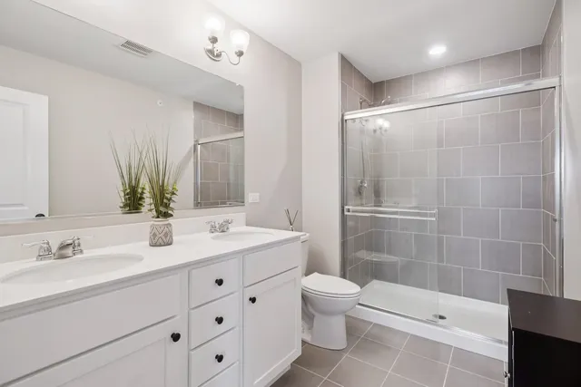 a bathroom with a double vanity sink toilet and shower