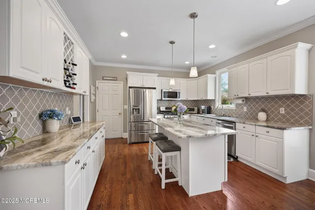 a kitchen with stainless steel appliances granite countertop a refrigerator a sink dishwasher a stove and white countertops with wooden floor