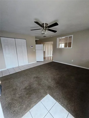 a view of an empty room with a ceiling fan and window