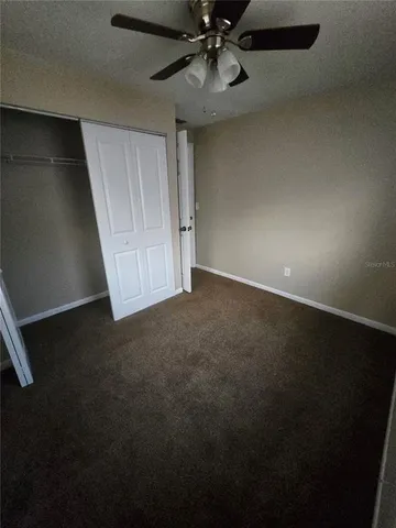 an empty room with a ceiling fan and window