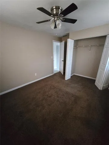 an empty room with a ceiling fan and window