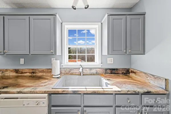 a kitchen with granite countertop a sink window and cabinets