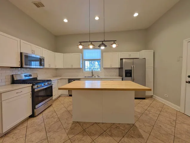 a large kitchen with granite countertop a stove a sink a refrigerator and a microwave