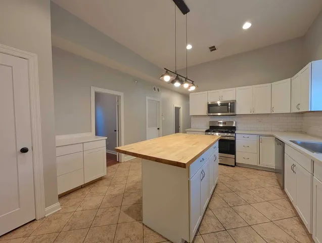 a kitchen with granite countertop a sink and dishwasher a stove top oven with white cabinets