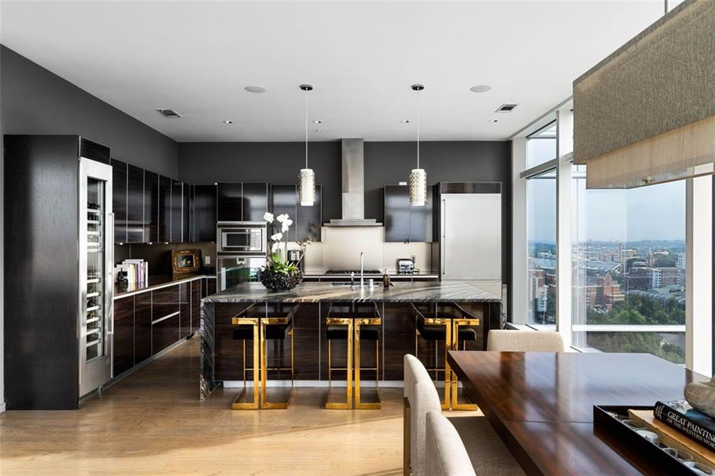 45 Ivan Allen Jr Boulevard Northwest, Unit 1702 Atlanta, GA 30308 - Photo 20 of 94 a kitchen with stainless steel appliances kitchen island granite countertop a table chairs sink and refrigerator