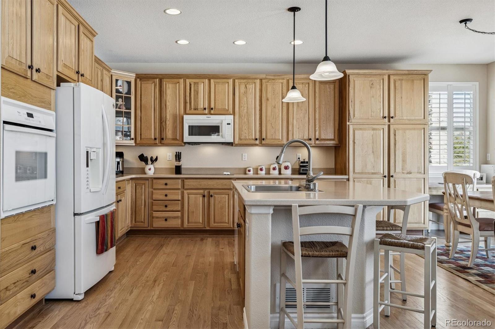 10822 Glengate Circle Highlands Ranch, CO 80130 - Photo 5 of 47 a kitchen with stainless steel appliances granite countertop a refrigerator a sink dishwasher a stove and white cabinets with wooden floor