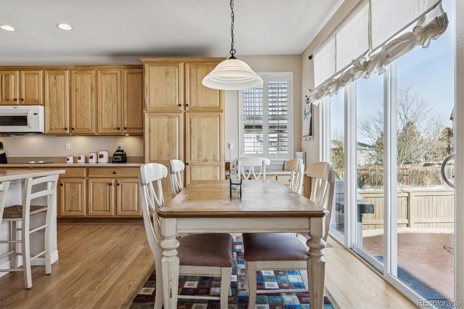 10822 Glengate Circle Highlands Ranch, CO 80130 - Photo 7 of 47 a kitchen with stainless steel appliances granite countertop a stove top oven a refrigerator a sink and a dining table with wooden floor