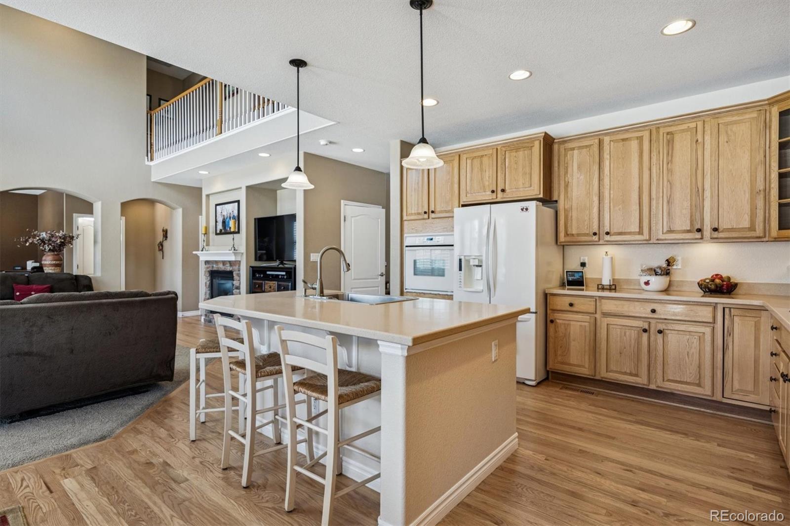 10822 Glengate Circle Highlands Ranch, CO 80130 - Photo 9 of 47 a kitchen with stainless steel appliances kitchen island granite countertop a refrigerator a stove a sink and white cabinets with wooden floor
