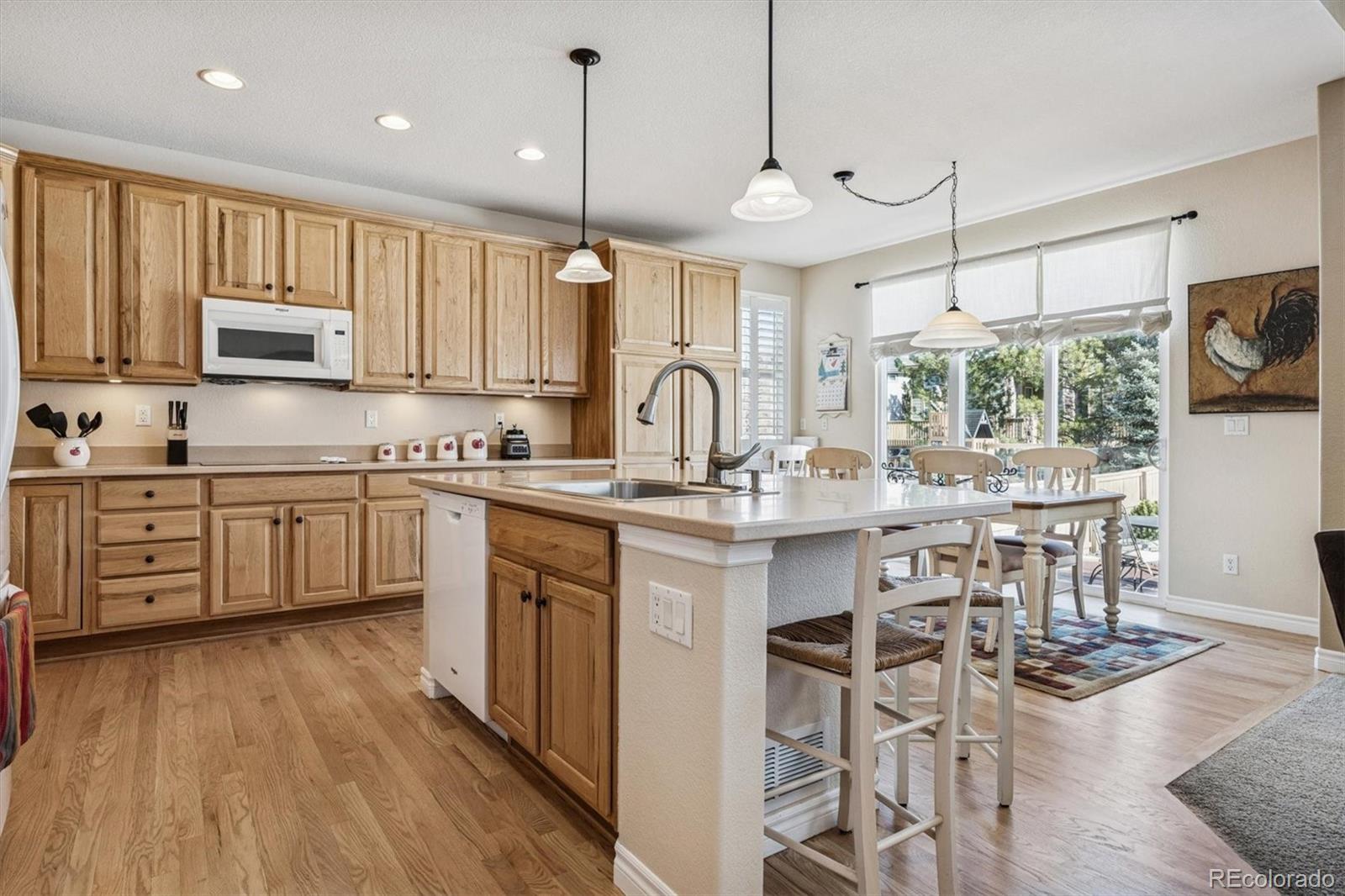 10822 Glengate Circle Highlands Ranch, CO 80130 - Photo 10 of 47 a kitchen with stainless steel appliances granite countertop a stove top oven a sink dishwasher a dining table and chairs with wooden floor