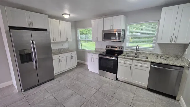 a kitchen with stainless steel appliances granite countertop a refrigerator stove a sink dishwasher and microwave