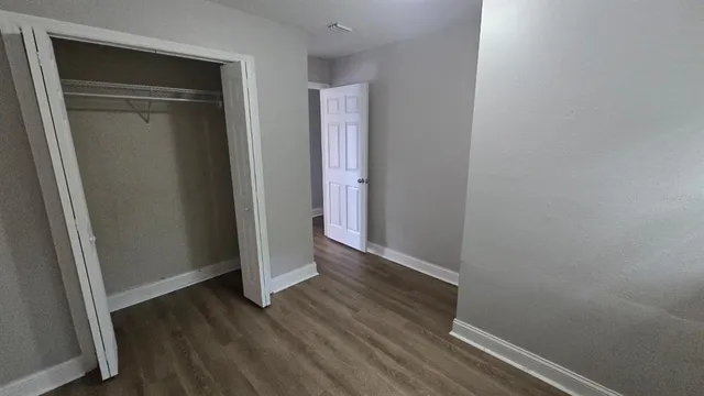 an empty room with wooden floor and closet