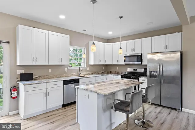 a kitchen with stainless steel appliances a sink a stove a refrigerator cabinets and wooden floor