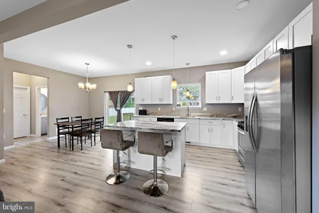 a kitchen with kitchen island granite countertop a center island a refrigerator and a dining table